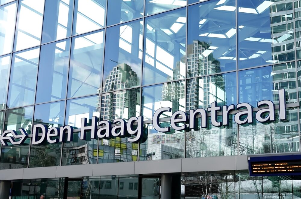 De voorgevel van Den Haag Centraal met in de reflectie de beursgebouwen en doorschijnend het wiebertjesdak.