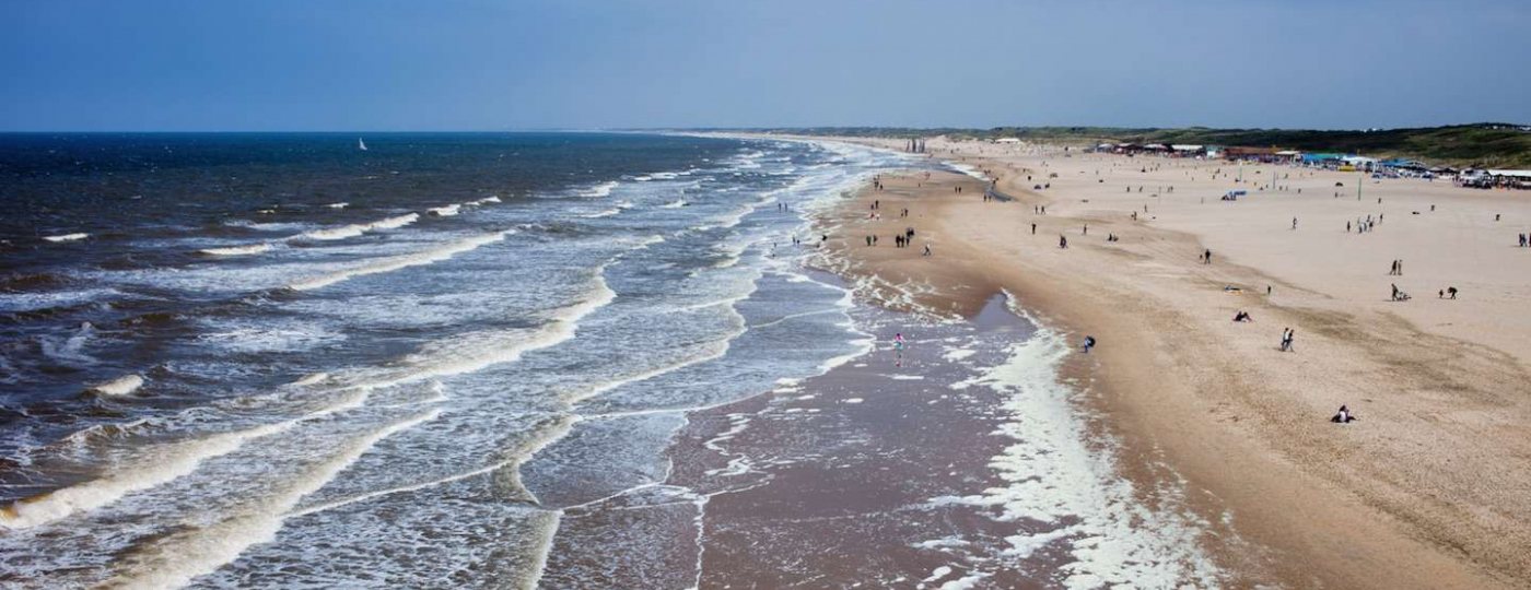 Scheveningen Strand vergezicht met links de Noordzee en rechts het strand met mensjes zo groot als mieren