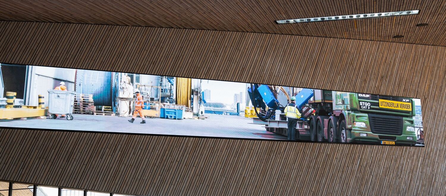 Het grote digitale scherm in de hal van Station Rotterdam Centraal. Hierop te zien zijn beelden gemaakt in de Rotterdamse Haven.